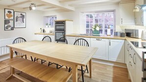 A modern kitchen with white cabinets, a wooden dining table, and a built-in oven. - Host Stay Middle Farmhouse (Whitby)