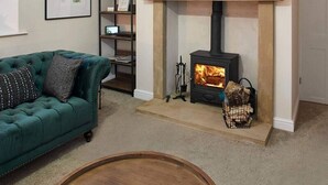 A living room with a fireplace, a sofa, a TV mounted above the fireplace, and a bookshelf. - Host Stay Middle Farmhouse (Whitby)