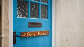 A blue door with a sign that reads "Gulls Haven" and a small metal mailbox above it.