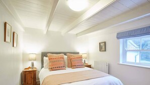 A bedroom with a large bed, two bedside tables, a window with a view, and a ceiling light.