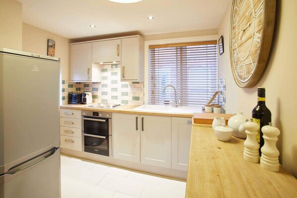 Enjoy cooking in this well-equipped kitchen with a stainless steel refrigerator, oven, and double sink.
