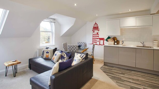A modern apartment with a loft-style living area, a kitchen with white cabinetry, and a red lighthouse wall decal. - Host Stay Number 3 at Pannett Apartments (Whitby)