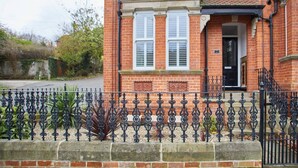 A brick house with a black iron fence, a front door, and a small porch. - Host Stay Number 3 at Pannett Apartments (Whitby)