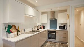 A modern kitchen with white cabinets, a built-in microwave, and a dishwasher. - Host Stay Number 3 at Pannett Apartments (Whitby)