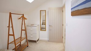 A room with a wooden clothes rack, a dresser, a mirror, and a door. - Host Stay Number 3 at Pannett Apartments (Whitby)