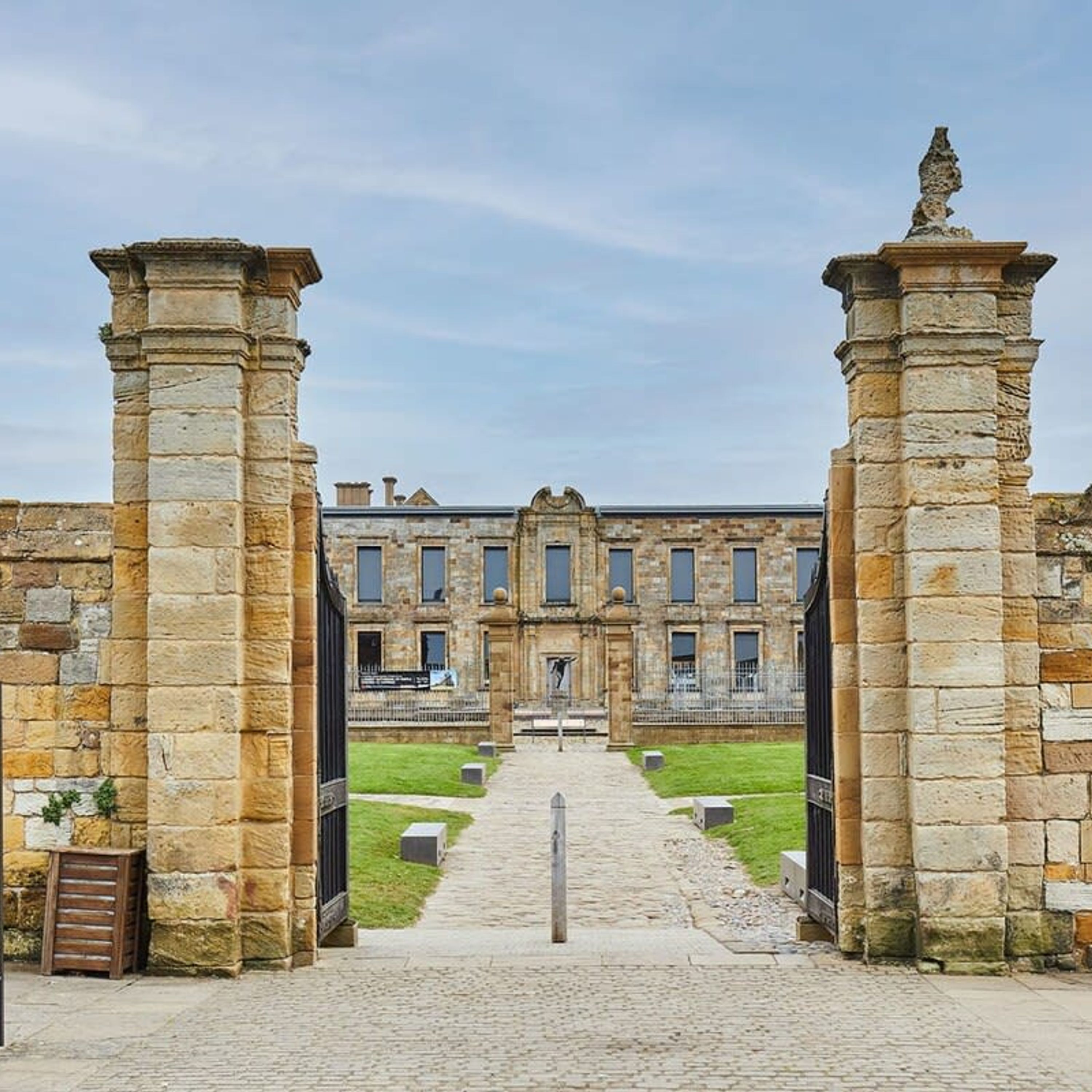 A historic building with a central courtyard, stone columns, and a statue on top.