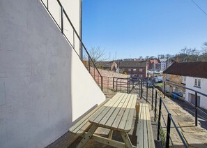 Stroll through this charming outdoor corridor, lined with a bench and a railing, leading to a vibrant city street.
