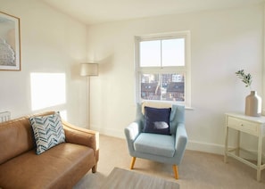 Relax in a stylish living room with a light blue armchair, brown leather sofa, and floor lamp.