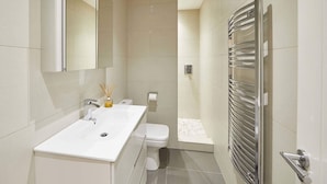 Un baño moderno con lavamanos, espejo y retrete blancos.