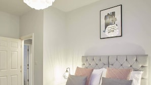 A bedroom with a large bed, a tufted headboard, and a framed picture on the wall.