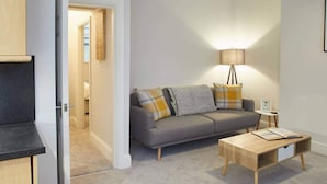 A modern living room with a grey sofa, a wooden coffee table, and a floor lamp.