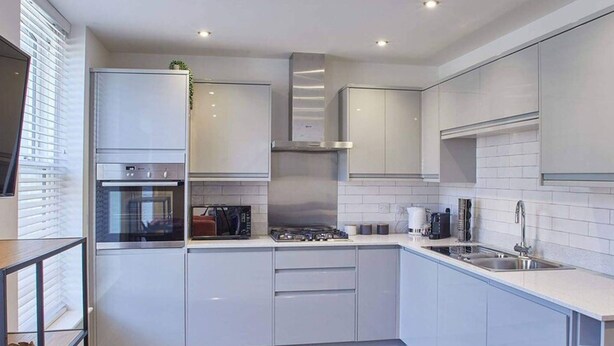 A modern kitchen with white cabinets, a built-in oven, and a stainless steel sink. - Host Stay Apartment Two Hudsons Yard House (Whitby)