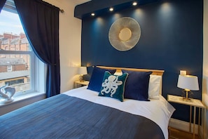 Relax in a spacious room with a large bed, dark accent wall, and decorative mirror.