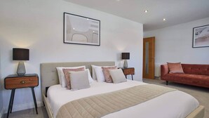 A bedroom with a large bed, two bedside tables, a red sofa, and two wall-mounted lamps. - Host Stay The View Hudsons Yard House (Whitby)