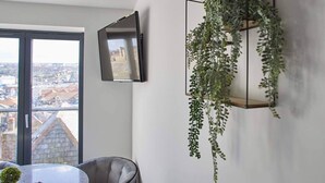 A modern room with a large window, a flat-screen TV mounted on the wall, and a hanging plant. - Host Stay The View Hudsons Yard House (Whitby)