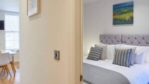 A bedroom with a large bed, a grey headboard, and a painting on the wall. - Host Stay The Old Sweet Shop (Whitby)