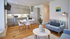 A modern living room with a light blue sofa, a white coffee table, and a dining area with a white table and chairs. - Host Stay The Old Sweet Shop (Whitby)