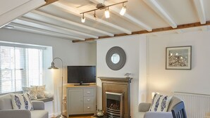 Un salon confortable avec une cheminée, un téléviseur et un coin repas comprenant une table et des chaises.
