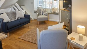 Une chambre de style « loft », avec un plafond en pente, un lit, un bureau et une fenêtre équipée de stores.