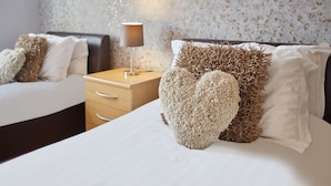 Una habitación de hotel con dos camas, una mesita de noche con lámpara y una pared con textura.