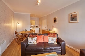 Relax in this inviting living room with a comfortable sofa, dining table, and fully equipped kitchen area.