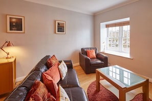 Relax in a stylish living room with a leather sofa, coffee table, and armchair, offering a view of the outside.