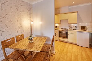 Enjoy cooking in the fully equipped kitchen with microwave, toaster, kettle, and oven, and dine in the adjacent dining area with a wooden table and chairs.