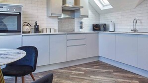 A modern kitchen with white cabinetry, a built-in oven, a microwave, and a skylight.