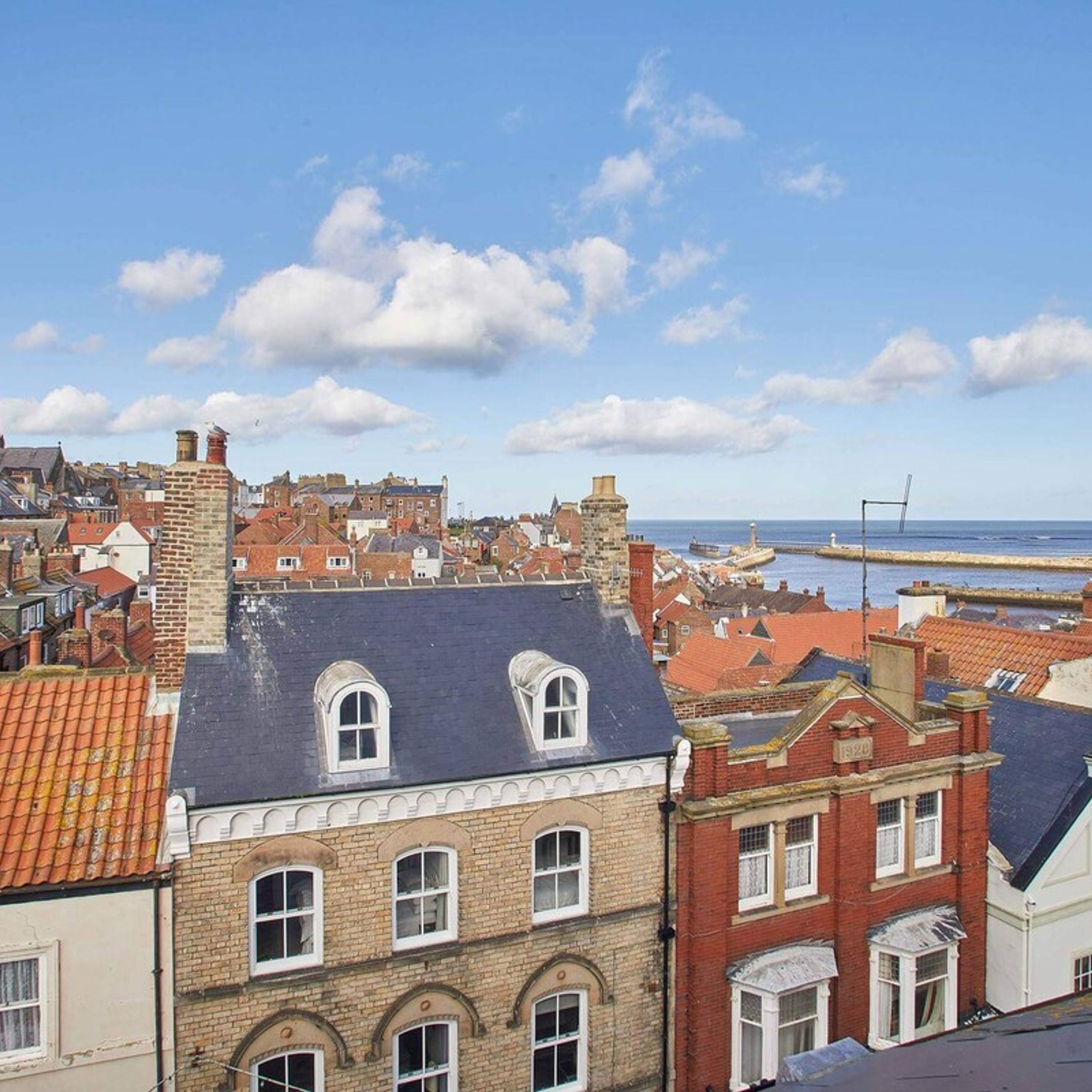 A coastal town with historic buildings, a harbor, and a clear sky.