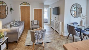 A modern living room with a sofa, armchair, and dining table. - Host Stay The Hampton at Prospect Hill Apartments (Whitby)