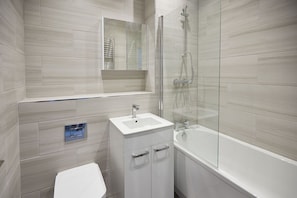 A modern bathroom with a glass-enclosed shower, a white sink, and a toilet.