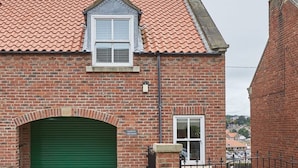 En murstensbygning med en grøn garageport, et lille vindue og en murstensbue.