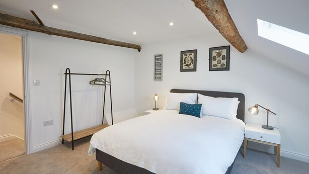 Ein Schlafzimmer mit einem Bett, einem Nachttisch, einem Wandregal und gerahmten Bildern.