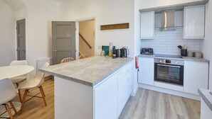 Eine moderne Küche mit weißen Schränken, einem Backofen und einer Kaffeestation.