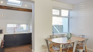 A modern kitchen with dark cabinets, a wooden countertop, and a window above the sink. - Host Stay Montrose View (Saltburn-by-the-Sea)