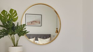 A desk with a potted plant, a round mirror, and a framed picture on the wall. - Host Stay Montrose View (Saltburn-by-the-Sea)