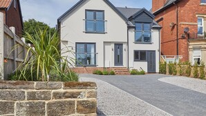 A two-story house with a paved driveway and a stone wall. - Host Stay The Madison at Prospect Hill Apartments (Whitby)