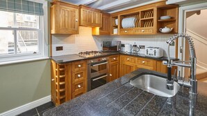 A compact kitchen with wooden cabinets, a granite countertop, stainless steel sink, and a built-in oven. - Host Stay Henderson House (Whitby)