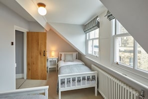 Cozy loft-style room with a single bed and window offering a view of the outside.