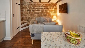 A cozy room with a stone wall, a sofa, a table with a fruit basket, and a staircase. - Host Stay Dolphin Cottage 1736 (Whitby)