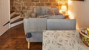 A cozy room with a stone wall, a sofa, a patterned tablecloth, and a fruit basket. - Host Stay Dolphin Cottage 1736 (Whitby)