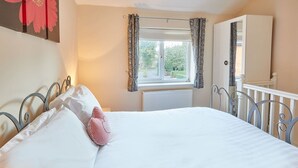 A bedroom with a bed, a window with curtains, a radiator, and a wardrobe. - Host Stay The Limes (Harrogate)