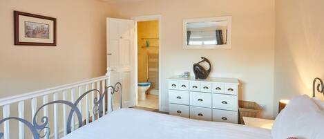 A bedroom with a bed, a dresser, a mirror, and a door leading to a bathroom.