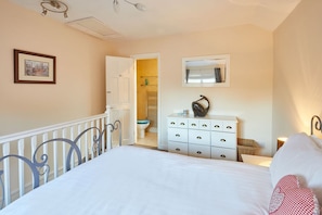 A bedroom with a bed, a dresser, a mirror, and a door leading to a bathroom. - Host Stay The Limes (Harrogate)