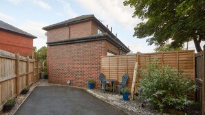 A brick house with a paved driveway, wooden fence, and potted plants. - Host Stay The Limes (Harrogate)
