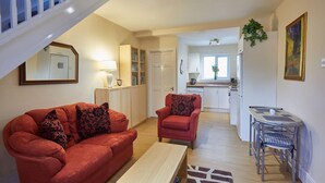 A living room with a red sofa, a matching armchair, a coffee table, and a dining area with a small table and chairs. - Host Stay The Limes (Harrogate)