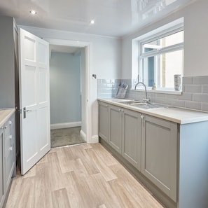 Enjoy cooking in this well-equipped kitchen with a sink and a door leading to another room.