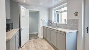 Eine moderne Küche mit grauen Schränken, einer Holz Arbeitsplatte und einem Fenster mit Stranddekoration.