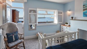 A room with a view of the sea, a rocking chair, a crib, and a dresser. - Host Stay No 3 Sandside (Whitby)