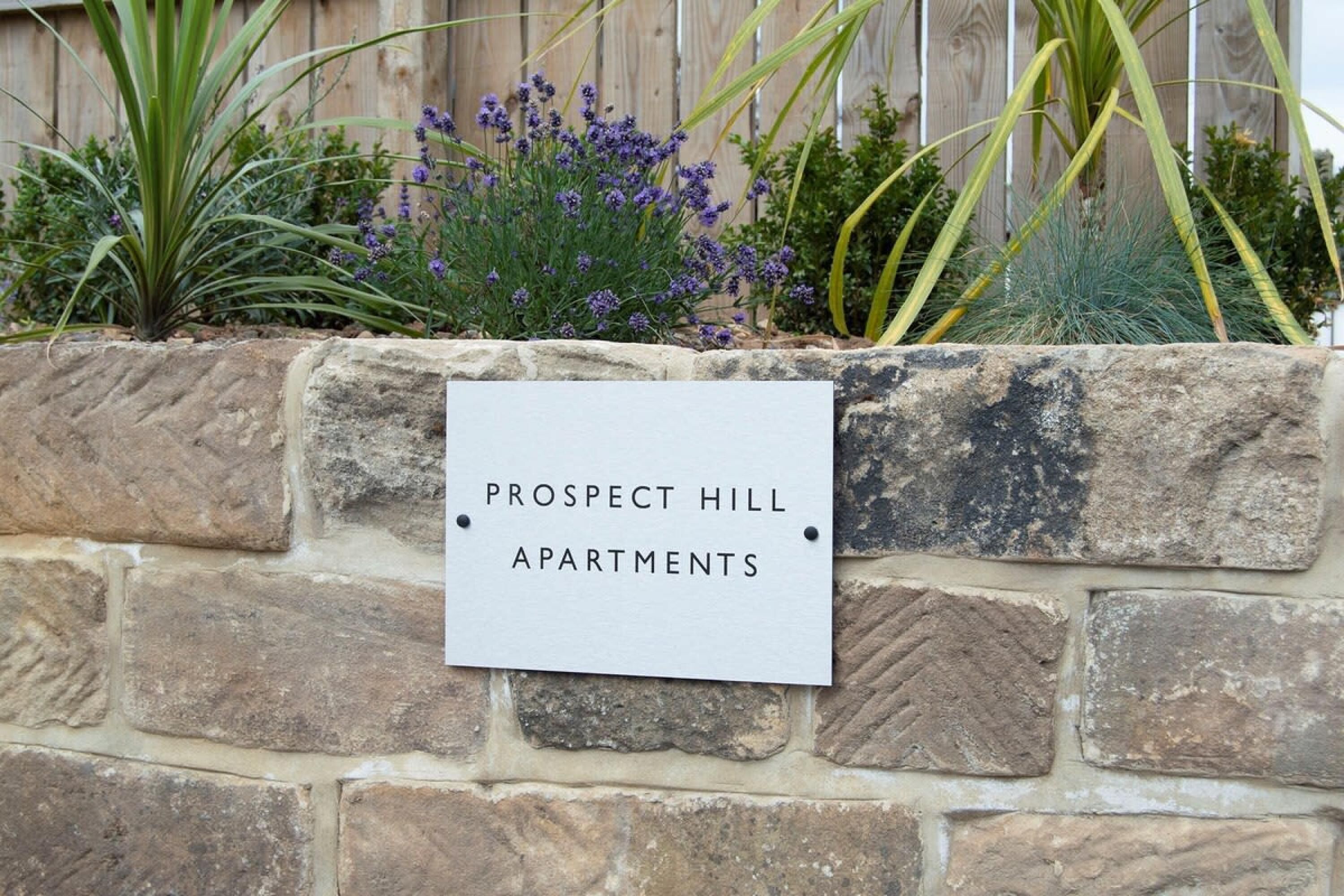 Eine Steinmauer mit einem Schild, auf dem Apartments Prospect Hill steht.